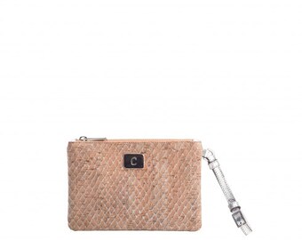 May include: A small cork clutch bag with a silver zipper and a silver strap. The bag has a diamond pattern and a black leather patch with the letter "C" on the front.