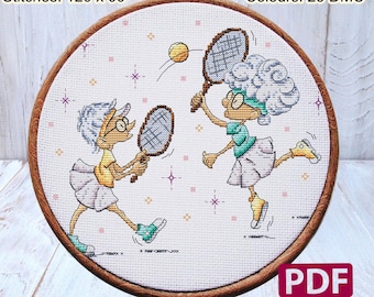 May include: A cross stitch pattern featuring two women playing tennis. The pattern is in a round hoop with a wooden frame. The pattern is on white Aida cloth with a light blue background. The women are wearing colorful clothing and have white hair. The pattern includes 25 DMC colors and is 8.57 inches by 7.07 inches.