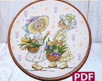 May include: Cross stitch pattern featuring two women holding baskets of flowers. The pattern is 8.36 inches by 7.07 inches and uses 36 DMC colors. The pattern is titled "Sweet Annet" and includes a PDF download.