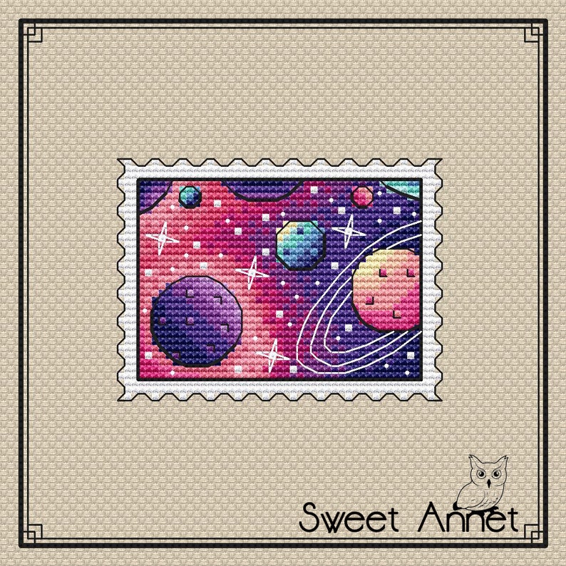 May include: A colorful space-themed cross-stitch pattern with planets, stars, and a galaxy background. The pattern is framed by a white border with a scalloped edge.