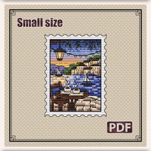May include: Cross stitch pattern stamp titled "Coffee at Sunset." The design features a small size image of a seaside cafe scene with a table, chairs, and sailboats. The pattern measures 2.5 x 3.3 inches (6.3 x 8.5 cm).