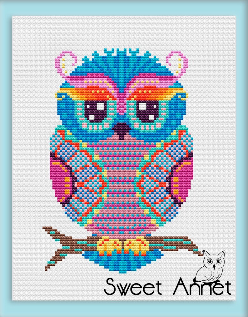 May include: A vibrant cross-stitch owl design in blue, pink, orange, and yellow, perched on a brown branch. The owl features large, square eyes against a white backdrop. The text "Sweet Annet" is displayed at the bottom of the image.