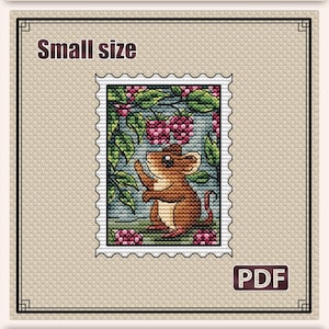 Może przedstawiać: Wzór haftu krzyżykowego przedstawiający brązową mysz w ogrodzie z malinami. Projekt to obrazek przypominający znaczek z napisem "Mouse in the Garden". Rozmiar wzoru to 6,3 x 8,5 cm.