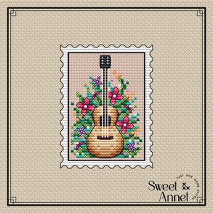 May include: A cross-stitch pattern featuring a brown acoustic guitar with a floral design. The guitar is surrounded by pink, red, and green flowers. The pattern is framed by a white border with a decorative edge.