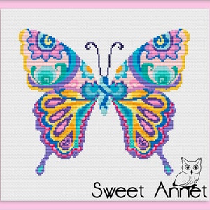 May include: A cross-stitch design of a butterfly with detailed patterns. The butterfly has symmetrical wings in pink, yellow, blue, and purple. The text "Sweet Annet" is at the bottom, accompanied by an owl illustration.