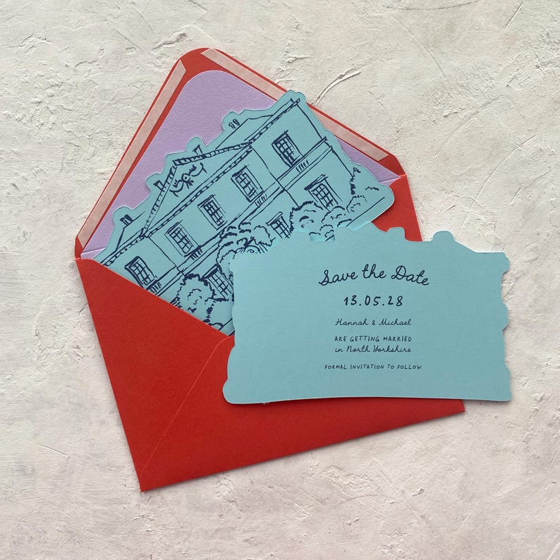 May include: A red envelope with a light purple interior holds a blue card with a house illustration and the text "Save the Date". The card also includes the date 13.05.28 and the names Hannah & Michael.