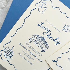 May include: Cream-coloured wedding invitation with navy blue illustrations and text. The invitation features the names "Lucy & Andy", the date "Saturday 4th September 2027", and the location "Parley Manor in Hampshire". Decorative elements include doves and a table setting.