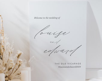 Puede incluir: Un cartel de boda blanco con el texto "Bienvenido a la boda de Louise y Edward" y la ubicación "The Old Vicarage" y el hashtag "#louiseandedward2024".