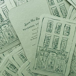 May include: Sage green wedding invitations with a hand-drawn illustration of a building facade. The text "Save the Date" and event details are printed on the cards. The building illustration includes the text "PLANTERS INN".