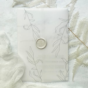 May include: A white invitation suite with a translucent overlay. The overlay has black line-drawn botanical illustrations. A silver wax seal with a leaf design secures the overlay. The design has an elegant, minimalist aesthetic.