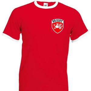 May include: Red t-shirt with a white ringer and a white crest featuring a dragon and the word "ORIENT" on the left chest.