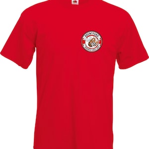 May include: A vibrant red t-shirt with short sleeves, showcasing a small circular badge on the chest. The badge features a cartoon bee and the words "Brentford" and "Unhinged Since 1889" in a circular arrangement.