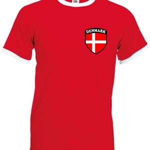 May include: Red t-shirt with a white ringer and a white and red Danish flag on the left chest with the word "DENMARK" above it.