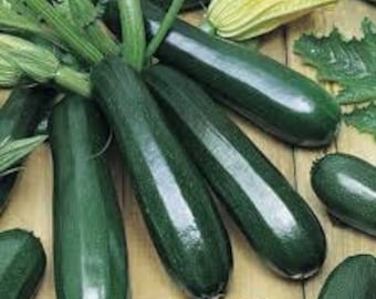 May include: A group of dark green zucchini squash with a few yellow flowers. The zucchini are arranged on a wooden surface.