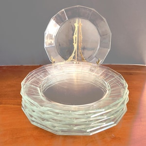 May include: A stack of six clear glass dinner plates with a geometric design around the edge.