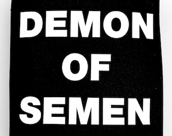 Op de afbeelding: Zwarte neopreen-blikjeskoeler met witte tekst die "DEMON OF SEMEN" luidt en een klein wit logo dat "KUNTY" onderaan staat.