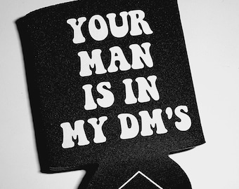 May include: Black and white can cooler with the text "YOUR MAN IS IN MY DM'S" in white, bold letters. The bottom of the cooler has a small white logo that says "KUNTY".