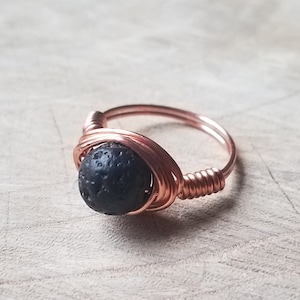 May include: A copper wire wrapped ring with a black lava rock bead.