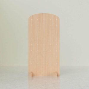 A light wood arched pegboard display stand with evenly spaced holes, standing upright on two support feet, centered against a light background.
