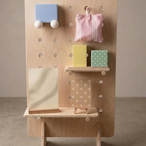 A light wood pegboard display stand with various small, colorful decorative items and shelves, including a blue block, pink striped bag, and yellow box.