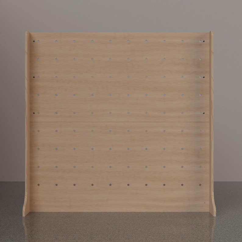 May include: A light-colored wooden pegboard display stand featuring a grid of evenly spaced circular holes across its flat surface. The structure includes two side panels that extend forward, providing stability for the upright rectangular board.