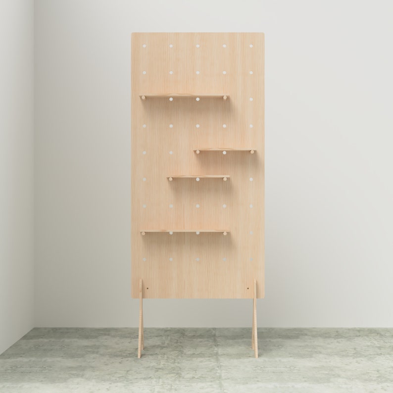 K&ouml;nnte beinhalten: Eine hellfarbene Holz-Ausstellungs-Tafel mit mehreren kleinen Regalen. Die Tafel hat ein Gitter aus gleichm&auml;&szlig;ig verteilten L&ouml;chern und wird von zwei abgewinkelten Beinen getragen. Die Regale sind in unterschiedlichen H&ouml;hen angeordnet.
