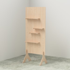 K&ouml;nnte beinhalten: Ein helles Holzregal mit drei Regalen und einem Lochwand-Design. Die Regale werden von kleinen Stiften getragen und das Ger&auml;t steht auf zwei abgewinkelten Beinen. Das Ger&auml;t besteht aus hellem Holz.