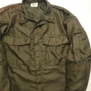 May include: A green utility jacket with a zipper closure and two large pockets on the front. The jacket has a label that reads "Army Cloth" and "Made in Korea".