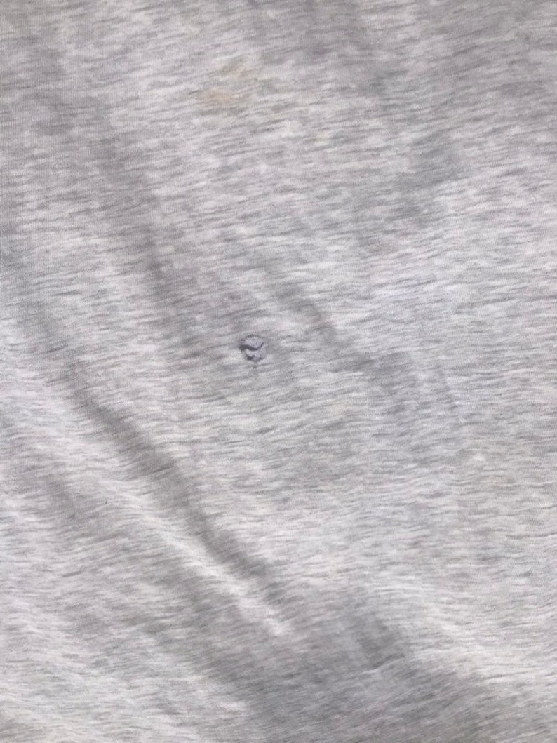 May include: A close-up of a grey, textured fabric with a small hole in the centre.