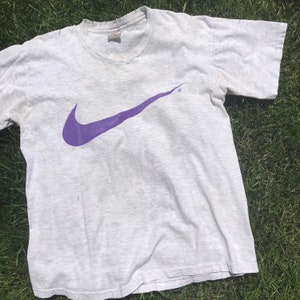 May include: A vintage grey t-shirt with a purple Nike swoosh logo.