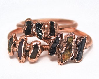 May include: Two copper rings with black and green gemstone accents. The rings are stacked on top of each other.