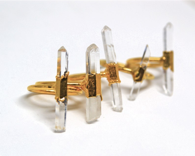K&ouml;nnte beinhalten: Drei goldene Ringe mit klaren Quarzkristallspitzen. Die Ringe sind &uuml;bereinander gestapelt.