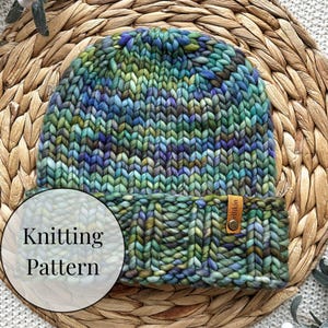 May include: A hand-knitted beanie in shades of green, blue, and purple. The hat has a ribbed brim and a small leather tag. The text "Knitting Pattern" is overlaid on the image.