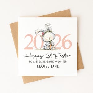 May include: A square greeting card with a watercolor illustration of a bunny holding a carrot. The card has the text "Happy 1st Easter" and "To a special granddaughter Eloise Jane" in black script. The year "2026" is in pink.