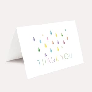 May include: A white thank you card with a colorful raindrop design. The text "THANK YOU" is written in rainbow colors.