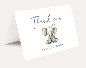 May include: A white thank you card with blue text that says "Thank you" and a watercolor illustration of a gray elephant wearing a blue outfit. The text "Baby Stuhlman" is printed below the elephant.