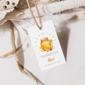 May include: A white gift tag featuring a watercolour illustration of a honey jar and yellow flowers. The tag includes the text "THANK YOU" and "FOR SHOWERING ME WITH SWEET LOVE!" with the name "Alice" and the date "OCTOBER 20, 2024".