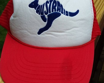 May include: A red and white trucker hat with a blue kangaroo logo. The kangaroo is made up of the word "Australia".