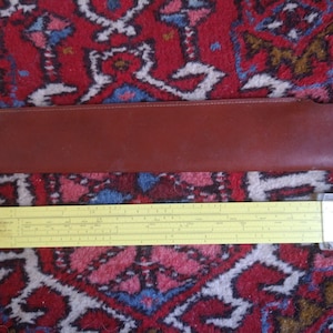 May include: A yellow slide rule with a brown leather case. The slide rule is a tool used for mathematical calculations.