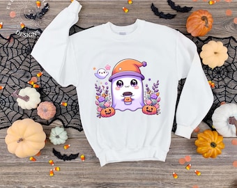 May include: White sweatshirt featuring a cute cartoon ghost wearing an orange hat and holding a coffee cup. The ghost is surrounded by pumpkins, flowers, and stars, with the text "EVERYDAY EM DESIGNS" on the top left.