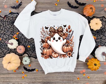 May include: White sweatshirt featuring a Halloween-themed graphic. The design includes a cute ghost with a leopard print bow, surrounded by pumpkins and flowers. The text "EVERYDAY EM DESIGNS" is visible on the left side.