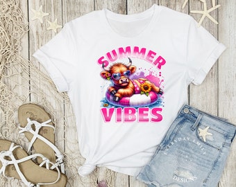 May include: White t-shirt featuring a cartoon cow wearing sunglasses and a floral floatie, with the words "SUMMER VIBES" in pink. The shirt is styled with denim shorts and sandals, evoking a summer theme.