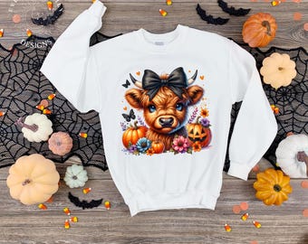 May include: White sweatshirt featuring a colorful graphic of a Highland cow with a black bow, surrounded by pumpkins, flowers, and butterflies. The design has a Halloween theme, with jack-o'-lanterns and candy corn accents.