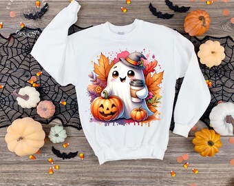 May include: White sweatshirt featuring a cartoon ghost wearing a witch hat and holding a coffee cup, with a jack-o'-lantern and fall leaves. The design is surrounded by pumpkins, bats, and candy corn, perfect for Halloween.