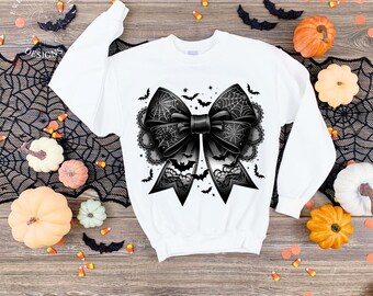 May include: White sweatshirt featuring a large black bow design with spiderwebs, bats, and lace details. The bow is the focal point, perfect for Halloween or gothic-themed apparel. The design is centered on the front of the long-sleeved top.