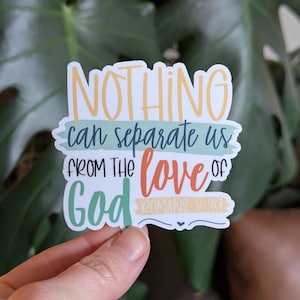May include: A sticker with the text "NOTHING can separate us FROM THE love OF God" in various colors. The text is layered on a white background with a green and yellow border. The sticker also includes the text "ROMANS 8:39".