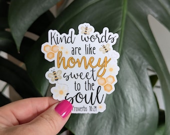 May include: A white sticker with the text "Kind words are like honey sweet to the soul" in black and yellow script. The sticker features illustrations of bees and honeycomb. The Bible verse Proverbs 16:24 is printed at the bottom.