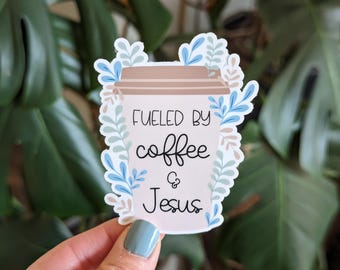 May include: A white coffee cup with the text "Fueled by coffee & Jesus" surrounded by blue and brown floral designs.