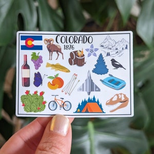 May include: A white sticker with a colorful illustration of various icons representing Colorado. The sticker features the state flag, a bighorn sheep, a bottle of wine, grapes, a trout, a peach, a mountain range, a ski lift, a fighter jet, a raft, a cactus, a bicycle, a tent, a dinosaur, and a pine tree. The text "COLORADO 1876" is printed in black at the top of the sticker.