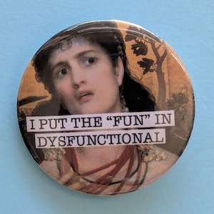 May include: Circular button featuring a vintage portrait of a woman with the text "I PUT THE "FUN" IN DYSFUNCTIONAL" in a white rectangle. The button has a shiny finish and is set against a light blue backdrop.
